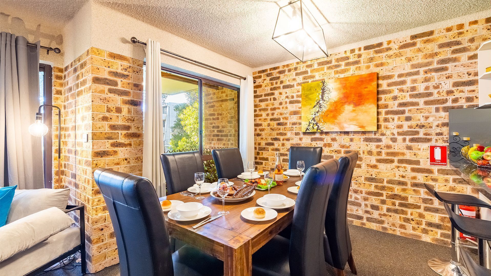 A dining area with a brick wall, a table set for four, and a fire extinguisher sign.