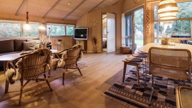 A spacious living area with a wooden ceiling, a large window, a dining table with chairs, and a television. - "Lovisa" - 500m from the sea by Interhome (Løkken)
