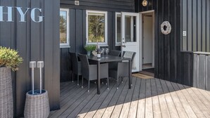A dark wooden exterior with a covered patio area featuring a table and chairs. - "Lovisa" - 500m from the sea by Interhome (Løkken)