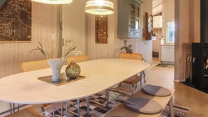 A dining area with a large round table, two hanging pendant lights, and a view into the kitchen. - "Lovisa" - 500m from the sea by Interhome (Løkken)