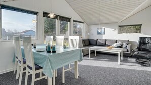 A spacious room with a dining table, chairs, a sofa, and a black leather chair. - "Ingward" - 300m to the fjord by Interhome (Tarm)