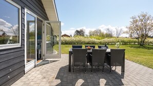 An outdoor patio with a table and chairs, a covered seating area, and a view of the surrounding garden. - "Ingward" - 300m to the fjord by Interhome (Tarm)