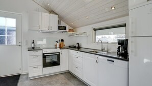 A modern kitchen with white cabinetry, a built-in oven, a microwave, and a coffee maker. - "Ingward" - 300m to the fjord by Interhome (Tarm)
