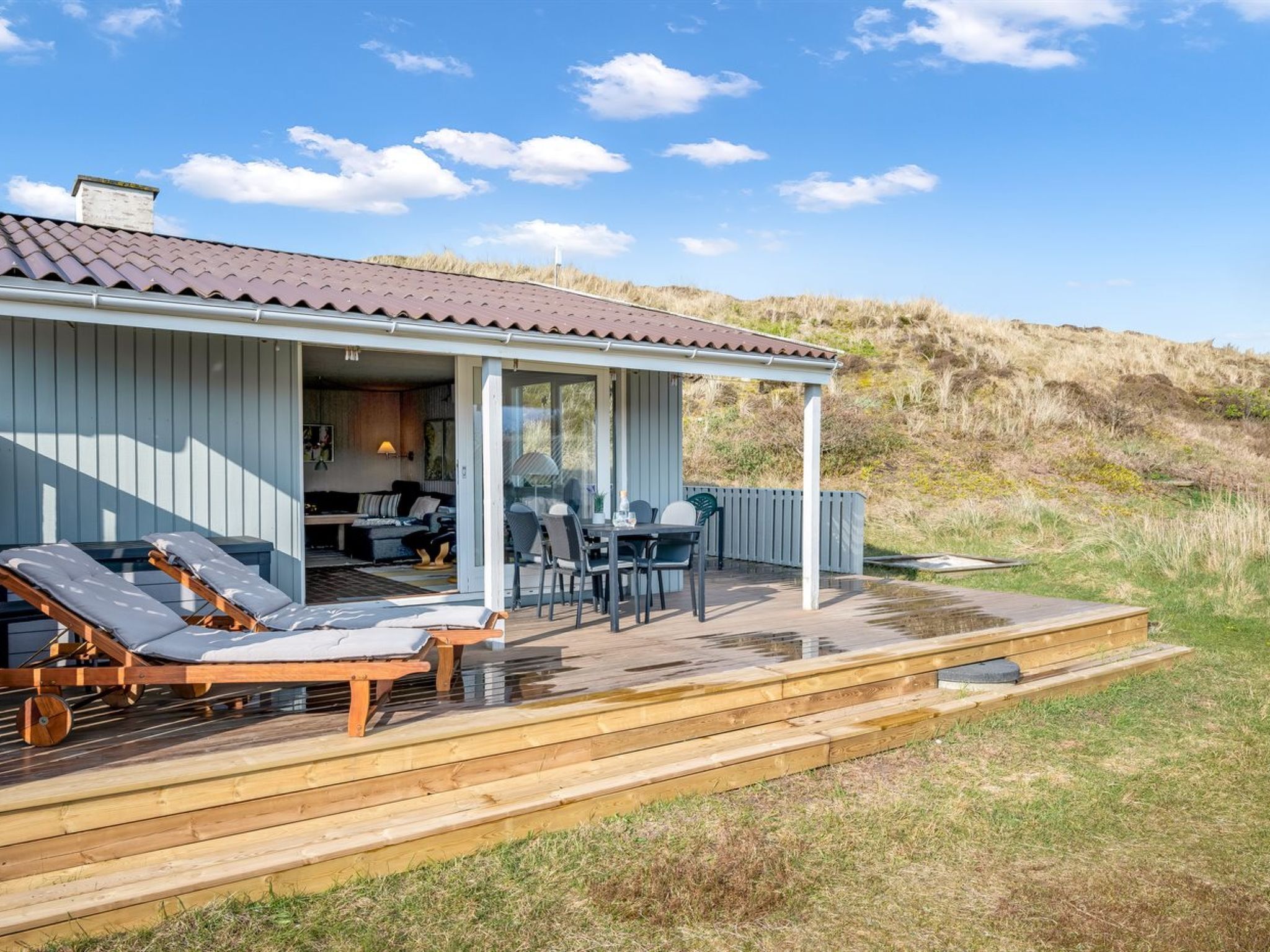 A coastal house with a deck, outdoor seating, and a covered patio.