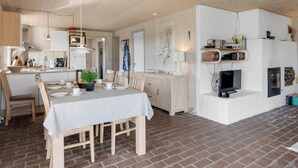 Eine moderne Küche mit Holzausstattung, einem gedeckten Esstisch und einem Boden aus Backsteinen.