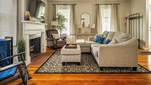 A living room with a fireplace, leather armchair, sofa, and patterned rug.