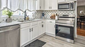A modern kitchen with white cabinets, stainless steel appliances, and a patterned backsplash.