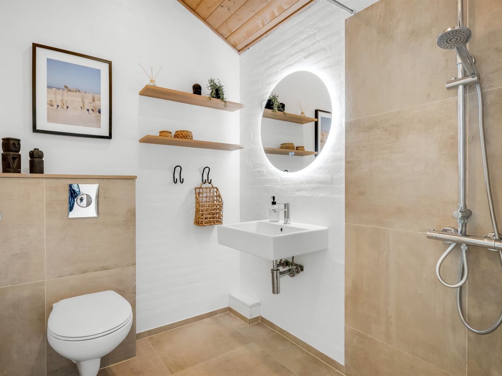 A modern bathroom with a toilet, a sink, a shower, and decorative shelves.