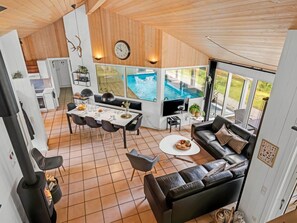 A modern interior with a dining area, a living room with a sofa, and a view of an outdoor swimming pool.