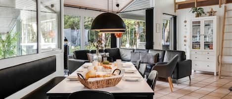 A modern dining area with a long table, black chairs, and a large black pendant light.
