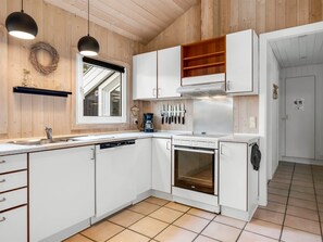 A compact kitchen with white cabinetry, a built-in oven, and a coffee maker. - "Jensen" - 700m to the fjord by Interhome (Oksbøl)