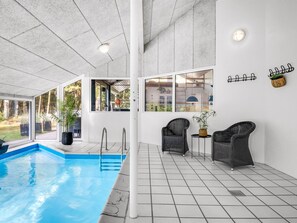 An indoor swimming pool with a tiled floor, two wicker chairs, and a window overlooking a garden. - "Jensen" - 700m to the fjord by Interhome (Oksbøl)