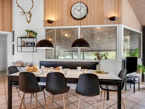 A modern dining area with a large table, black chairs, a clock, and a wall-mounted shelf with decorative items. - "Jensen" - 700m to the fjord by Interhome (Oksbøl)