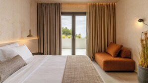 Une chambre d’hôtel moderne avec un grand lit, un canapé, une vue par une porte coulissante et une plante en pot.