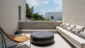 Un espace de détente extérieur moderne, comprenant un hamac, un pouf rond et un canapé avec des coussins.