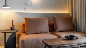 Une chambre moderne avec un canapé, une table d’appoint, une lampe et une petite table sur laquelle se trouve une tasse.
