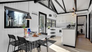 A modern kitchen with white cabinets, a central island, and a dining area with a table and chairs. - "Elisabeta" - 28km from the sea by Interhome (Toftlund)