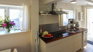 A modern kitchen with a central island, a built-in oven, and a window with curtains.