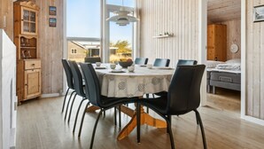 Un espace repas avec une table ronde, des chaises noires et une vue sur l’extérieur.