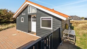 Une maison à deux étages, à l’extérieur gris et au toit orange, dot ée d’un petit porche et d’une fenêtre à cadre blanc.