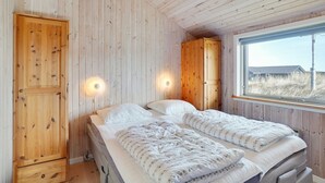 Une chambre avec deux lits, des murs en bois et une fenêtre donnant sur un beau paysage.