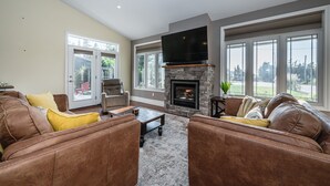 A living room with a stone fireplace, leather sofas, and large windows.