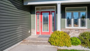 A house with a red front door, a small porch, and a stone foundation.