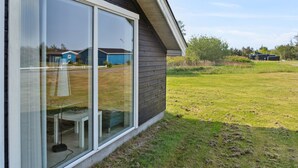 A modern house with large glass sliding doors, a grassy yard, and a clear sky. - "Jil" - 750m from the sea by Interhome (Hals)