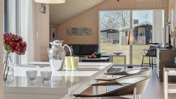 A modern kitchen with a central island, a dining area with a sofa, and a large window offering a view of the outdoors. - "Jil" - 750m from the sea by Interhome (Hals)