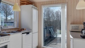 A modern kitchen with white appliances, a large window, and a sliding glass door leading to an outdoor deck. - "Jil" - 750m from the sea by Interhome (Hals)