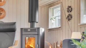 A cozy living room with a wood-burning stove, a leather chair, a sofa, and a window with a view. - "Jil" - 750m from the sea by Interhome (Hals)