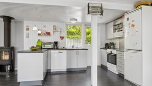 Eine moderne Küche mit weißen Schränken, einer zentralen Kochinsel, einem eingebauten Herd und einem Kühlschrank.