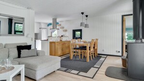 Un salon moderne comprenant un canapé, une table à manger et des chaises, un coin cuisine et une grande cheminée.