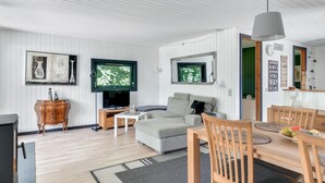 Un salon moderne avec un canapé, un téléviseur, une table à manger en bois et des chaises.