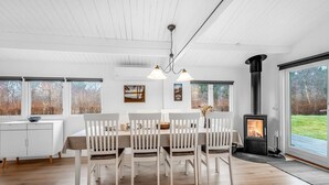 A modern dining area with a white table and chairs, a hanging light fixture, and a wood-burning stove. - "Staffan" - 200m to the fjord by Interhome (Skjern)