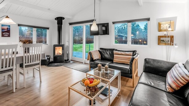 A spacious living room with a fireplace, a dining area, and large windows offering views of the outdoors. - "Staffan" - 200m to the fjord by Interhome (Skjern)