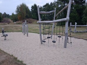 Un parque infantil con columpios, un tobogán y una estructura para escalar.