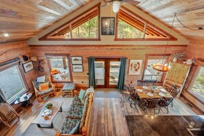 A spacious cabin with a high ceiling, wooden walls, and large windows.