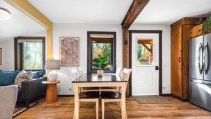 A modern kitchen with a wooden dining table, white chairs, and a stainless steel refrigerator. - Saddle n' Sage, 7 min to Glacier, Fire Pit (Coram)