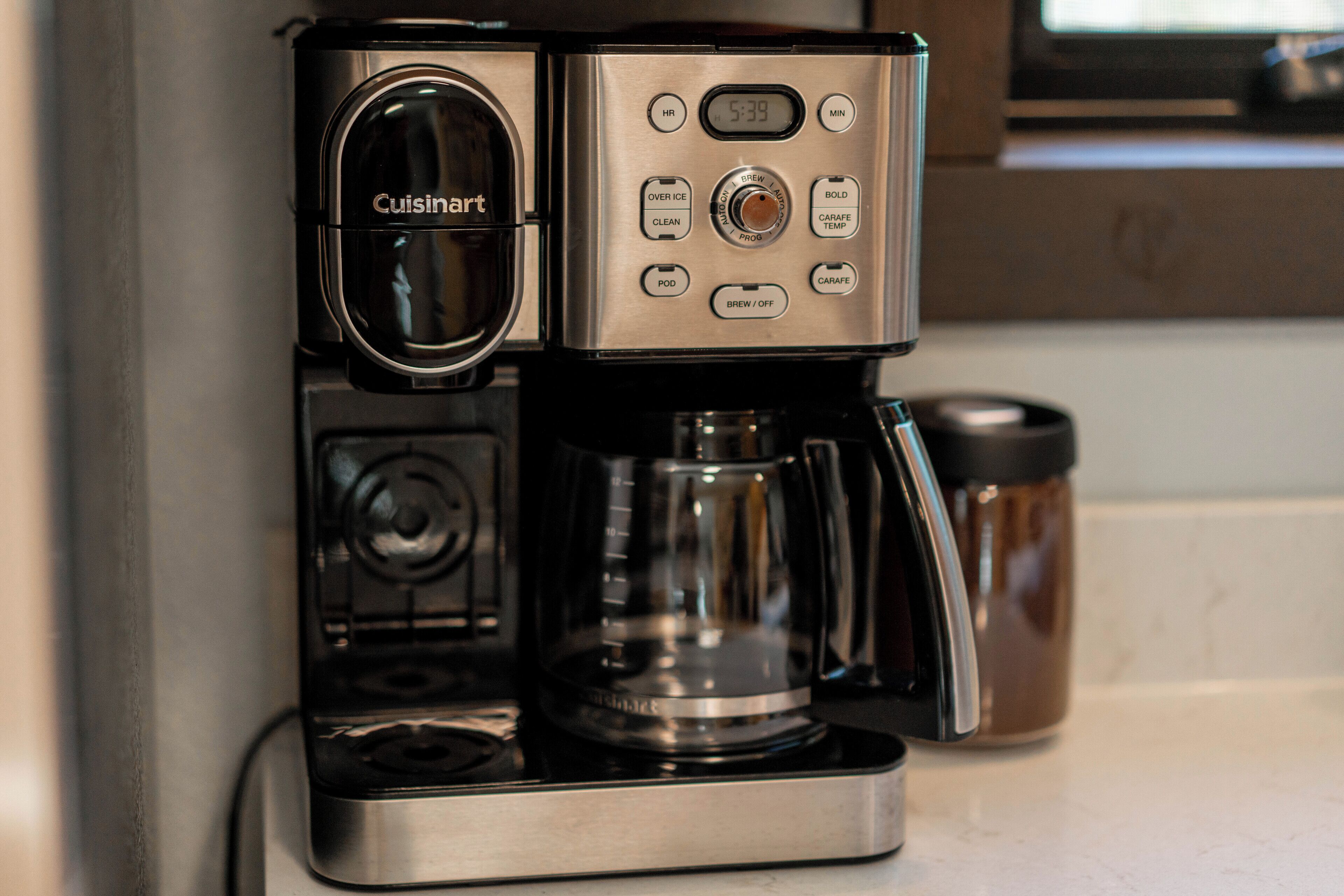 A Cuisinart coffee maker with a digital display, a pod holder, and a carafe.