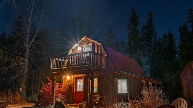 A cabin with a fire pit and outdoor seating, surrounded by trees. - Saddle n' Sage, 7 min to Glacier, Fire Pit (Coram)