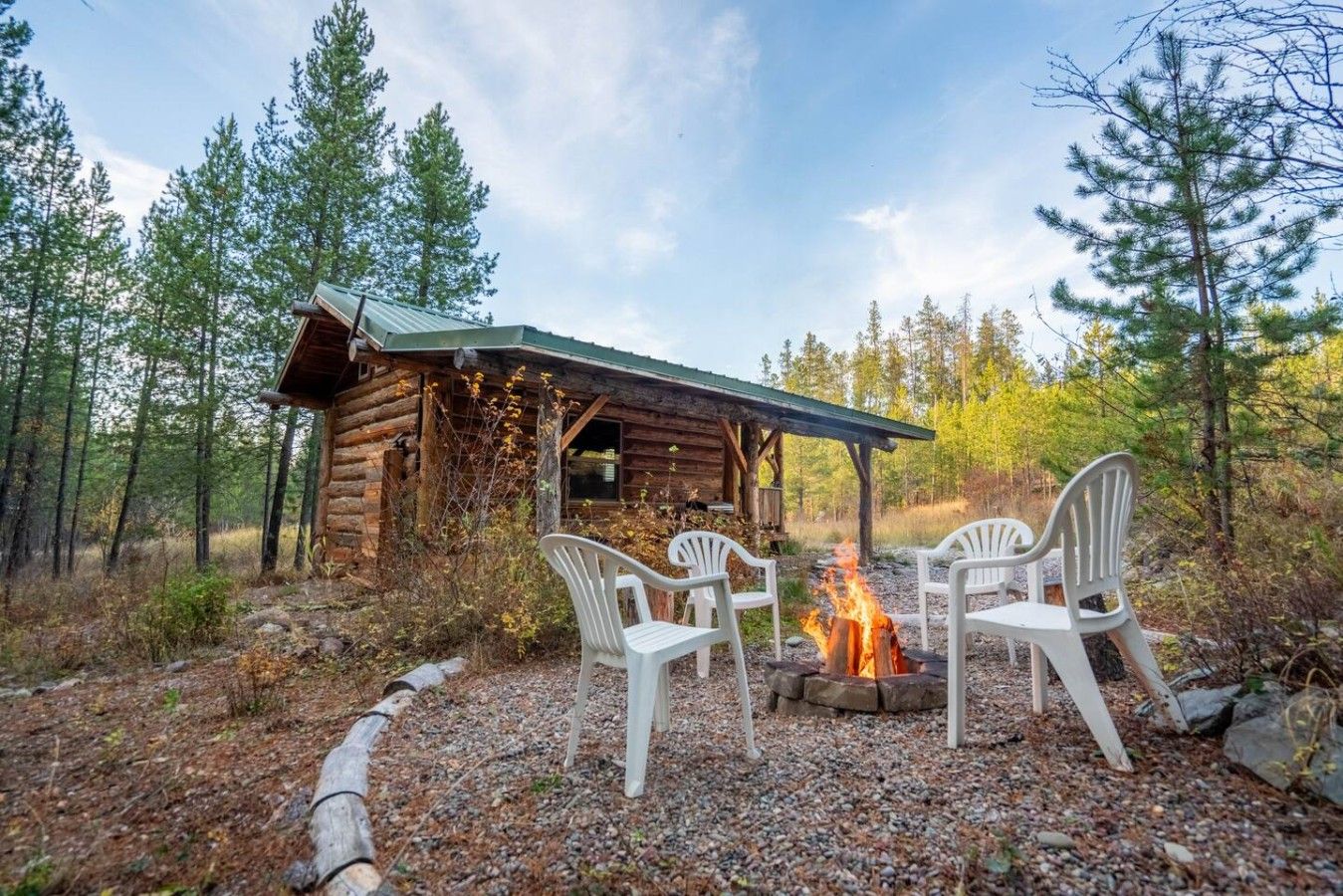 Eine rustikale Holzhütte mit Feuerstelle und Sitzgelegenheiten im Freien.