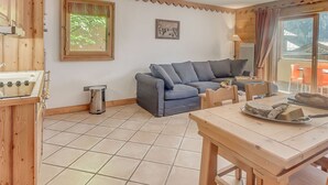 Un salon confortable avec un canapé bleu, une table à manger en bois et une petite cuisine équipée d’une cuisinière.