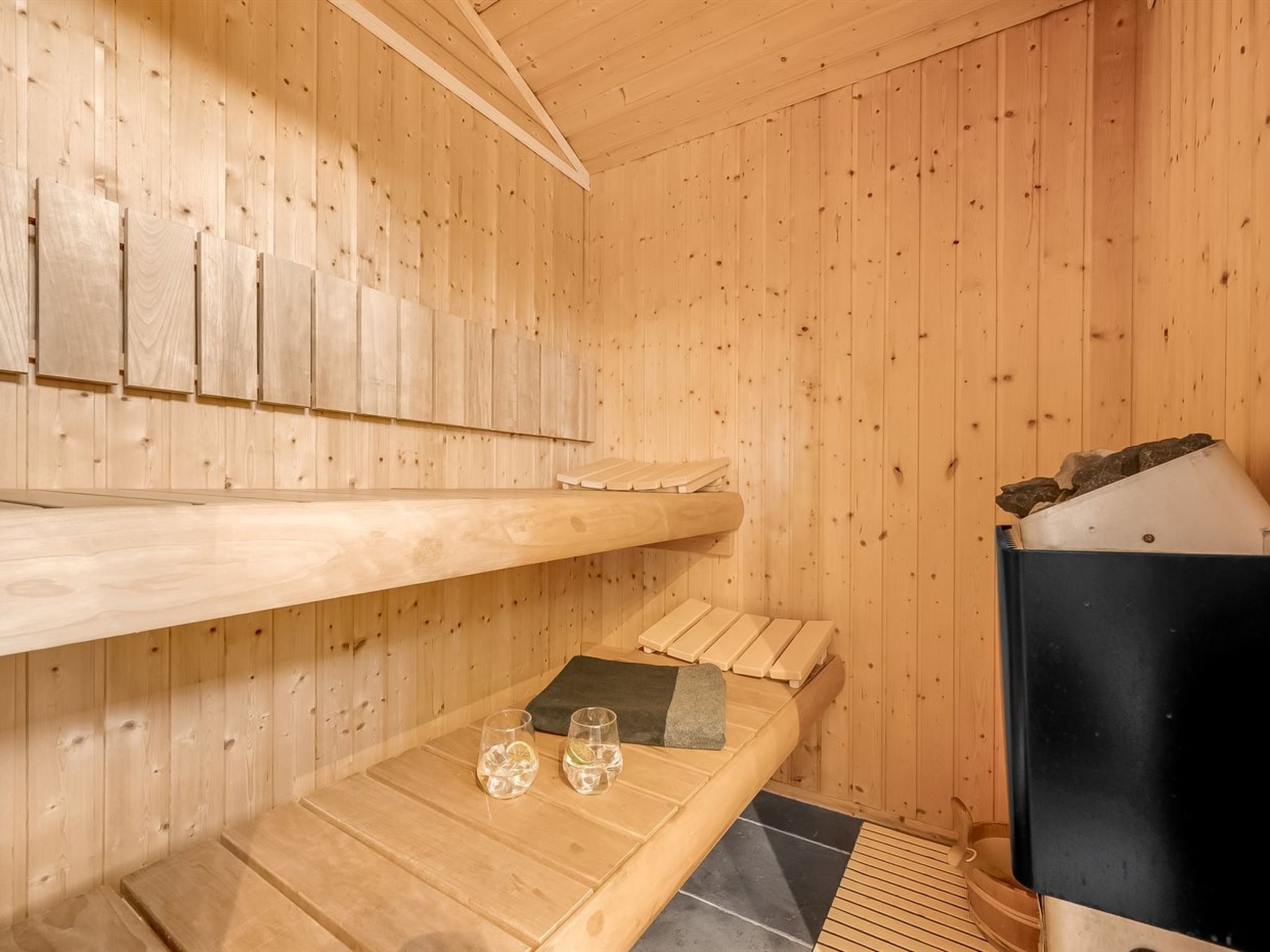 A wooden sauna room with benches and a sauna heater.
