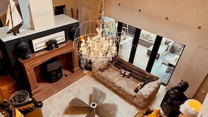A spacious living room with a large chandelier, a sofa, and a round table. - Riverside Country Retreat, Holiday Rental HotTub  Pizza Oven (Kirtlebridge)