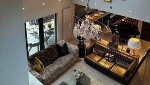 A modern living room with a high ceiling, a skylight, a chandelier, a piano, and a sofa. - Riverside Country Retreat, Holiday Rental HotTub  Pizza Oven (Kirtlebridge)