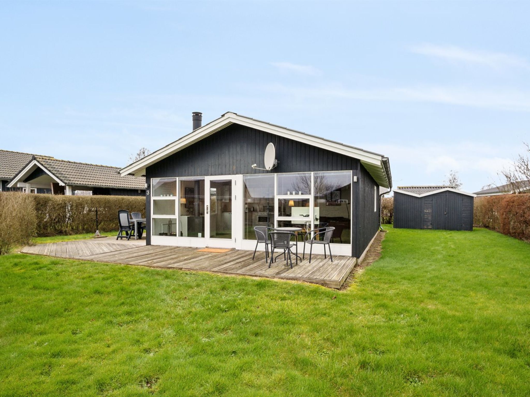 Ein modernes Haus mit einer großen Terrasse, einem Essbereich und einer Garage.