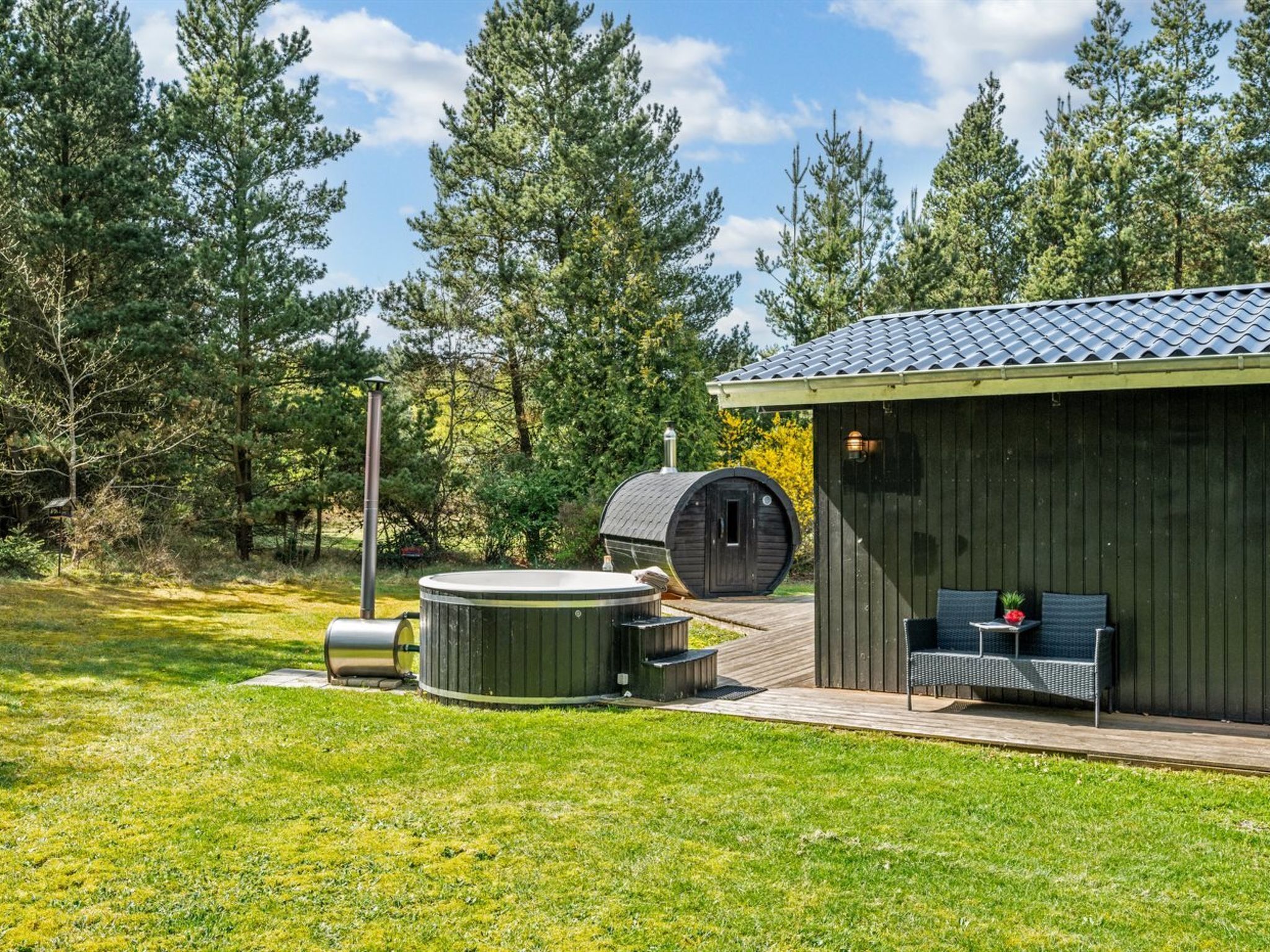 Uma cabana de madeira com hidromassagem, área de estar externa e sauna.