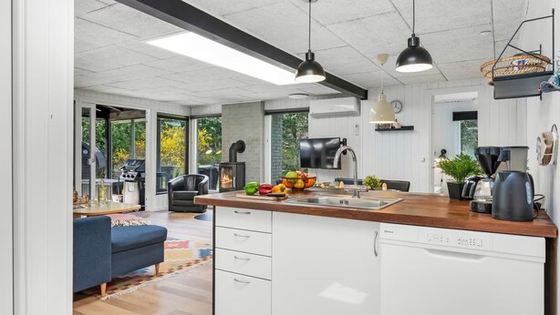 A modern kitchen with a central island, white cabinetry, and a dining area with a blue sofa. - "Eli" - 1.5km to the fjord by Interhome (Blåvand)