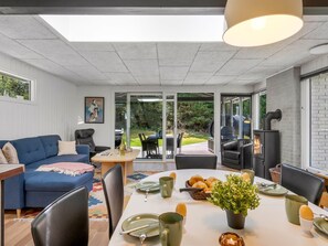 A modern interior with a dining area, a sofa, and a grill outside.